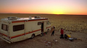Movie still from “Breaking Bad” (2008), created by Vince Gilligan – A couple of people standing in front of an rv in a field; Extreme Wide shot, Low angle