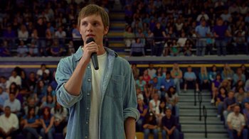 Movie still from “Breaking Bad” (2008), created by Vince Gilligan – A man holding a microphone while standing in front of an audience; Medium shot, Over the shoulder angle