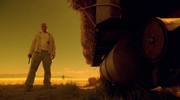 Movie still from “Breaking Bad” (2008), created by Vince Gilligan – A man standing in a field next to hay bales; Wide shot, Low angle