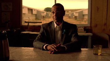 Movie still from “Breaking Bad” (2008), created by Vince Gilligan – A man sitting at a table in front of a window; Medium shot, Over the shoulder angle