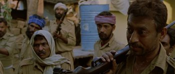 Movie still from “Paan Singh Tomar” (2012), directed by Tigmanshu Dhulia – A man holding a rifle in front of another man; Close Up shot, Over the shoulder angle