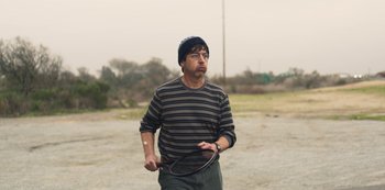 Movie still from “Paddleton” (2019), directed by Alex Lehmann – A man holding a tennis racquet in his hands; Medium shot, Over the shoulder angle