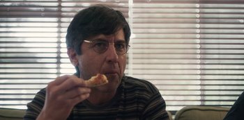 Movie still from “Paddleton” (2019), directed by Alex Lehmann – A man with glasses eating a piece of pizza; Close Up shot, Over the shoulder angle