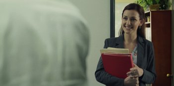 Movie still from “Paddleton” (2019), directed by Alex Lehmann – A woman in a suit holding a red folder; Medium shot, Over the shoulder angle