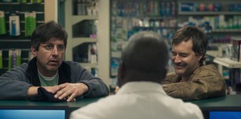 Movie still from “Paddleton” (2019), directed by Alex Lehmann – A group of people sitting around a table; Close Up shot, Over the shoulder angle