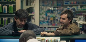 Movie still from “Paddleton” (2019), directed by Alex Lehmann – A couple of men sitting at a table in a store; Close Up shot, Over the shoulder angle