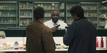 Movie still from “Paddleton” (2019), directed by Alex Lehmann – Two men are standing in front of a pharmacist talking to another man; Medium shot, Over the shoulder angle