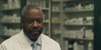 Movie still from “Paddleton” (2019), directed by Alex Lehmann – A man wearing a white lab coat in front of shelves of medicine; Close Up shot, Low angle