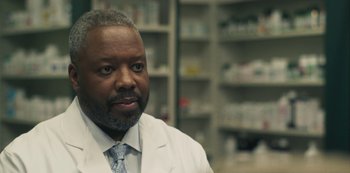Movie still from “Paddleton” (2019), directed by Alex Lehmann – A man wearing a lab coat in a room filled with shelves; Close Up shot, Low angle