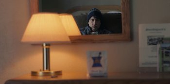 Movie still from “Paddleton” (2019), directed by Alex Lehmann – A man sitting in front of a mirror in a room; Medium shot, Over the shoulder angle