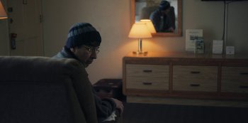 Movie still from “Paddleton” (2019), directed by Alex Lehmann – A man sitting in front of a mirror in front of a lamp; Medium shot, Over the shoulder angle