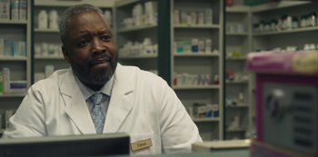 Movie still from “Paddleton” (2019), directed by Alex Lehmann – A man in white lab coat sitting at a table; Close Up shot, Over the shoulder angle