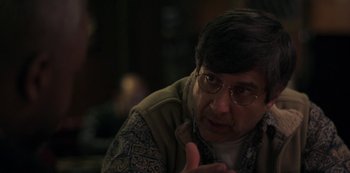 Movie still from “Paddleton” (2019), directed by Alex Lehmann – An older man wearing glasses is sitting down; Close Up shot, Over the shoulder angle
