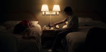 Movie still from “Paddleton” (2019), directed by Alex Lehmann – A man sitting on a bed next to a woman in a bedroom; Medium shot, High angle