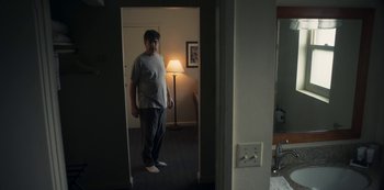 Movie still from “Paddleton” (2019), directed by Alex Lehmann – A man standing in a room with a lamp in the background; Medium shot, Low angle