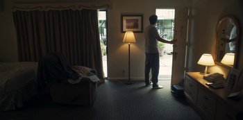 Movie still from “Paddleton” (2019), directed by Alex Lehmann – A man standing in front of an open sliding glass door; Wide shot, High angle