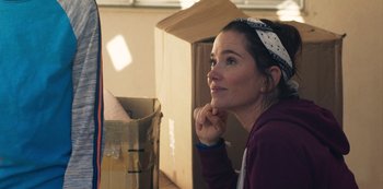 Movie still from “Paddleton” (2019), directed by Alex Lehmann – A woman sitting in front of a cardboard box; Close Up shot, Over the shoulder angle