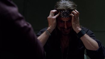 Movie still from “Breaking Bad” (2008), created by Vince Gilligan – A man with long blonde hair wearing a black shirt; Close Up shot, Overhead angle