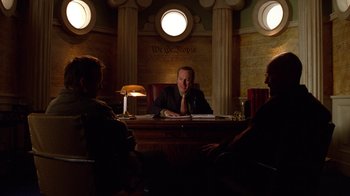 Movie still from “Breaking Bad” (2008), created by Vince Gilligan – Three people sitting at a table in a room; Medium shot, Low angle