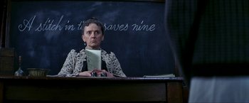 Movie still from “Peter Pan” (2003), directed by P.J. Hogan – A woman sitting at a desk in front of a chalkboard; Close Up shot, Low angle