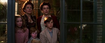 Movie still from “Peter Pan” (2003), directed by P.J. Hogan – A group of people standing around each other in front of a window; Medium shot, Low angle