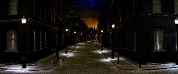 Movie still from “Peter Pan” (2003), directed by P.J. Hogan – A street scene at night with lights on the sidewalk; Extreme Wide shot, High angle