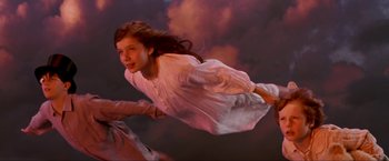 Movie still from “Peter Pan” (2003), directed by P.J. Hogan – A young girl flying through the air in a white dress; Medium shot, Overhead angle