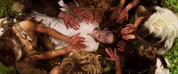 Movie still from “Peter Pan” (2003), directed by P.J. Hogan – A group of people surrounding a young girl in a white dress; Medium shot, Overhead angle