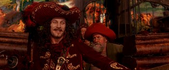 Movie still from “Peter Pan” (2003), directed by P.J. Hogan – A man dressed as a pirate with other men in the background; Medium shot, Over the shoulder angle