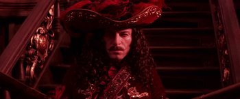 Movie still from “Peter Pan” (2003), directed by P.J. Hogan – A man in a red pirate costume and a red hat; Close Up shot, Over the shoulder angle
