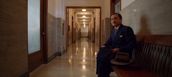 Movie still from “Ratched” (2020), created by Evan Romansky – A man in a suit sitting in the hallway of an office building; Wide shot, High angle