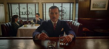 Movie still from “Ratched” (2020), created by Evan Romansky – A man sitting at a table in a restaurant; Medium shot, Low angle