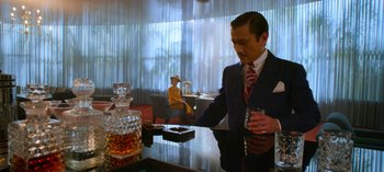 Movie still from “Ratched” (2020), created by Evan Romansky – A man in a suit and tie holding a drink; Medium shot, Over the shoulder angle