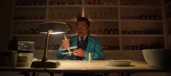 Movie still from “Ratched” (2020), created by Evan Romansky – A man sitting at a table in front of a lamp; Medium shot, Low angle