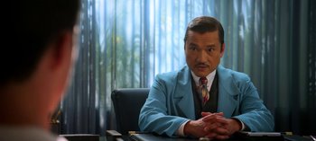 Movie still from “Ratched” (2020), created by Evan Romansky – A man sitting at a desk wearing a suit and tie; Medium shot, Low angle