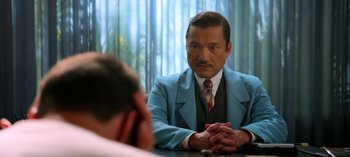 Movie still from “Ratched” (2020), created by Evan Romansky – A man in a blue suit sitting in front of another man; Medium shot, Over the shoulder angle