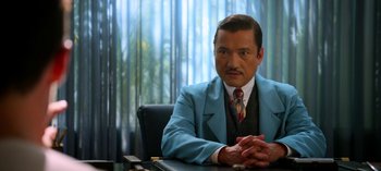 Movie still from “Ratched” (2020), created by Evan Romansky – A man sitting at a desk wearing a suit and tie; Medium shot, Over the shoulder angle