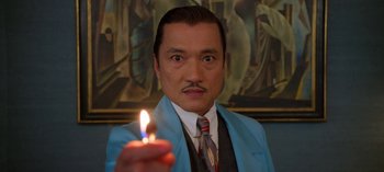 Movie still from “Ratched” (2020), created by Evan Romansky – A man holding a lit candle in front of a painting; Close Up shot, Low angle