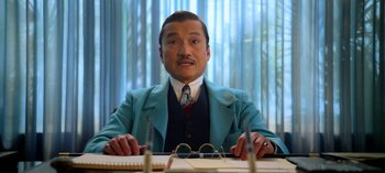 Movie still from “Ratched” (2020), created by Evan Romansky – A man sitting at a table wearing a suit and tie; Medium shot, Low angle