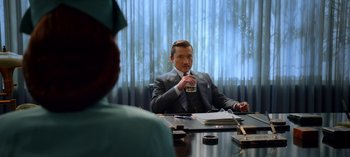 Movie still from “Ratched” (2020), created by Evan Romansky – A man sitting at a table with a drink; Medium shot, Over the shoulder angle