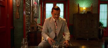 Movie still from “Ratched” (2020), created by Evan Romansky – A man sitting at a table with a glass of water in front of him; Medium shot, High angle