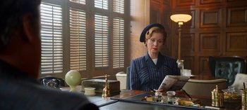 Movie still from “Ratched” (2020), created by Evan Romansky – A woman sitting at a table reading a newspaper; Medium shot, Over the shoulder angle