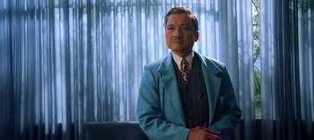 Movie still from “Ratched” (2020), created by Evan Romansky – A man wearing a suit and tie sitting in front of a window; Medium shot, Over the shoulder angle