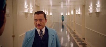 Movie still from “Ratched” (2020), created by Evan Romansky – A man in a suit and tie standing in a hallway; Medium shot, Low angle