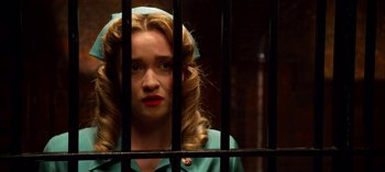 Movie still from “Ratched” (2020), created by Evan Romansky – A woman with blonde curly hair and a blue dress is behind bars; Close Up shot, Low angle