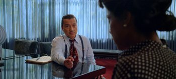 Movie still from “Ratched” (2020), created by Evan Romansky – An older man sitting at a table in front of an older woman; Medium shot, Over the shoulder angle