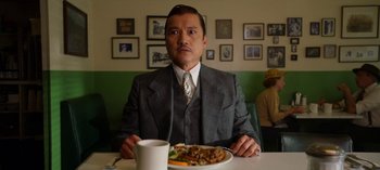 Movie still from “Ratched” (2020), created by Evan Romansky – A man sitting at a table in front of a plate of food; Medium shot, Over the shoulder angle