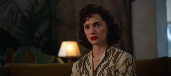 Movie still from “Ratched” (2020), created by Evan Romansky – A woman in a brown and white dress sitting in front of a lamp; Close Up shot, Over the shoulder angle