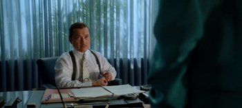 Movie still from “Ratched” (2020), created by Evan Romansky – A man sitting at a desk in front of papers; Medium shot, Over the shoulder angle