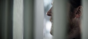 Movie still from “Red Rose” (2022), directed by Ramón Salazar – A man with a beard is looking out of a window; Extreme Close Up shot, Low angle